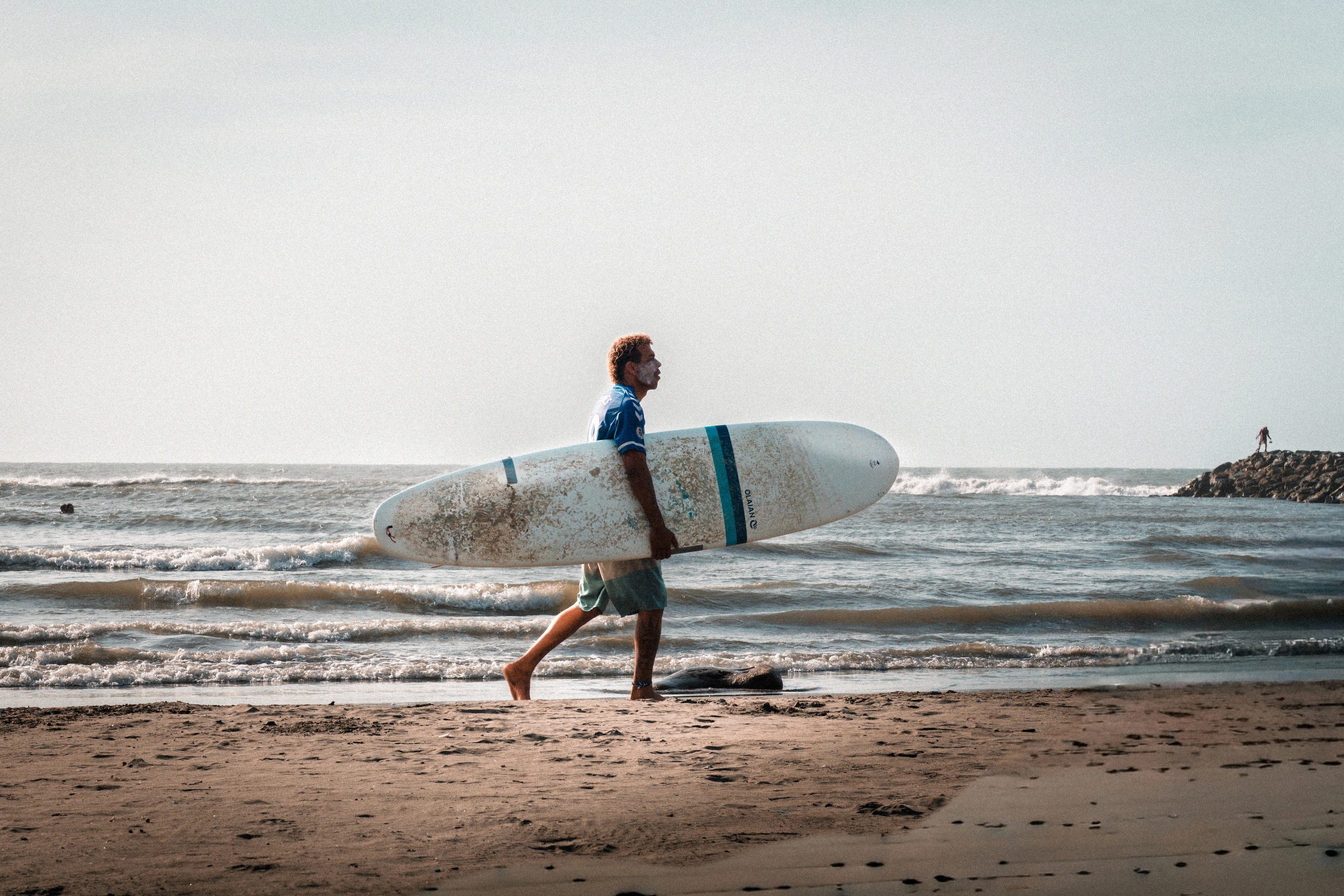 A surfer walking along the beach
