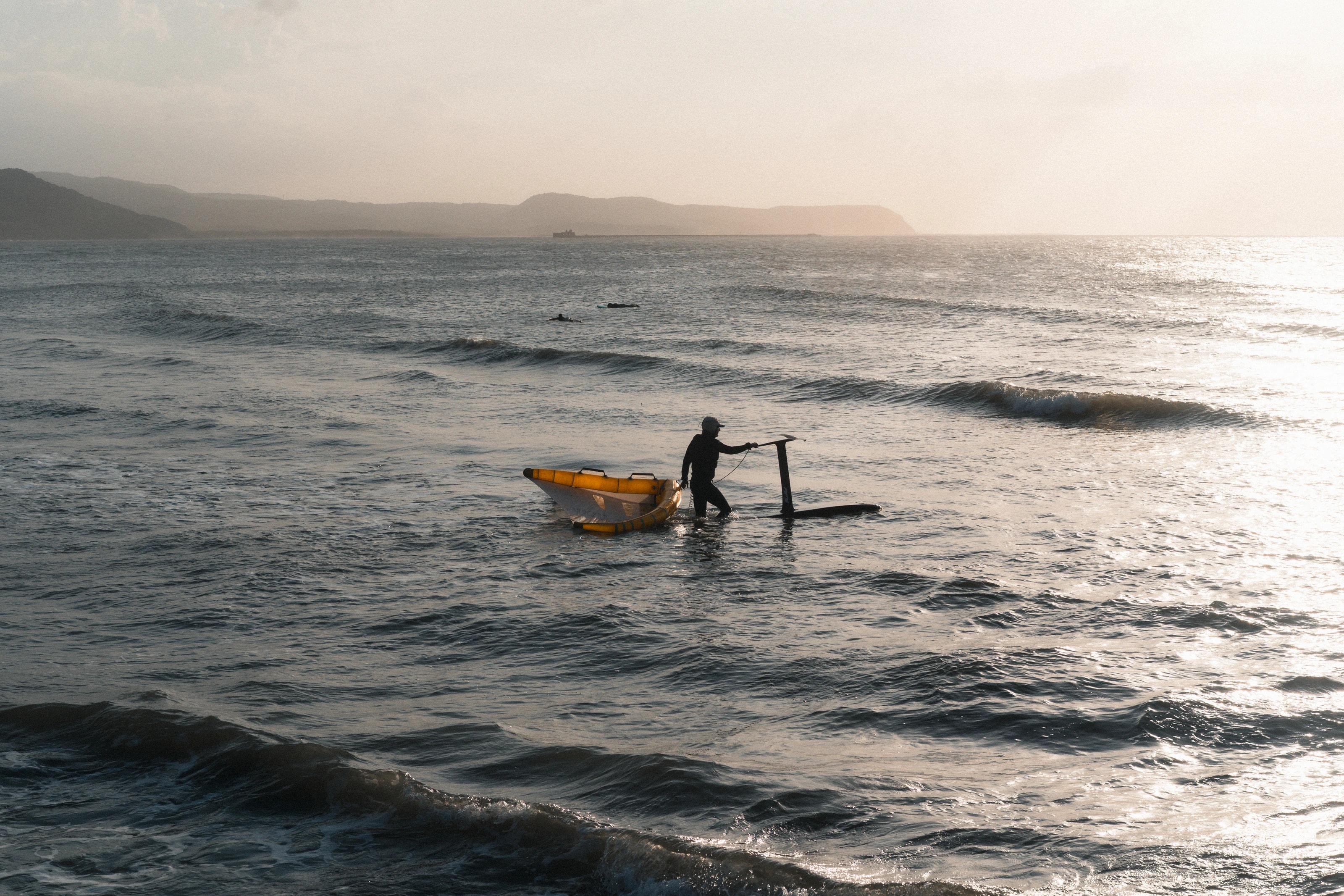 A person walking into sunlit surf